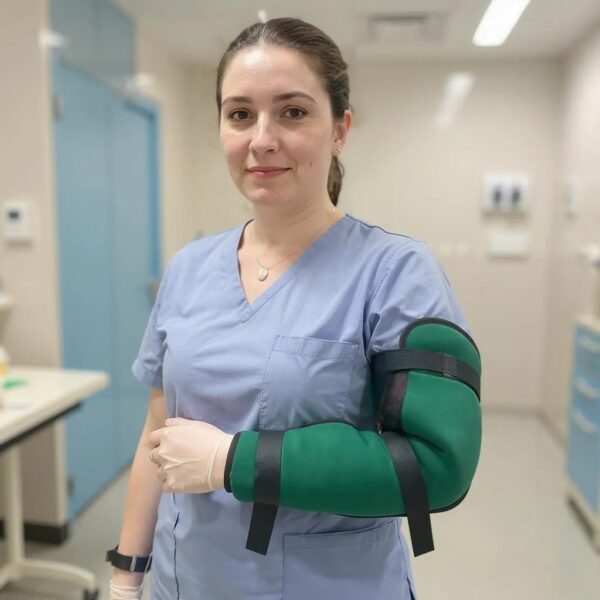 A nurse in the hospital smiling wearing the green padded upper limb protector on her arm.