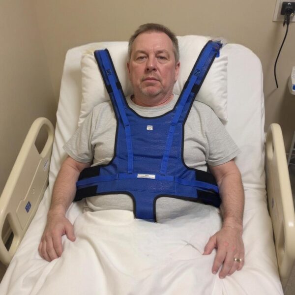 A patient in a hospital bed with the upper vest restraint attached.