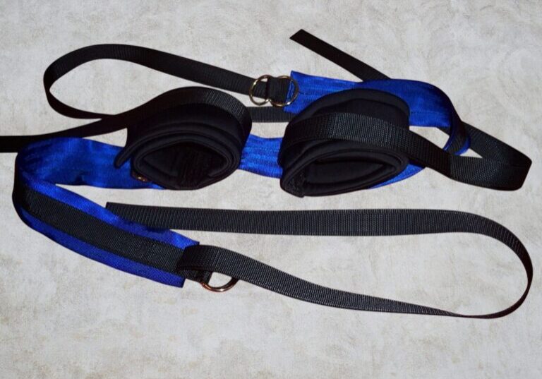 A black and blue strap with lycra cuffs attached to a hospital bed