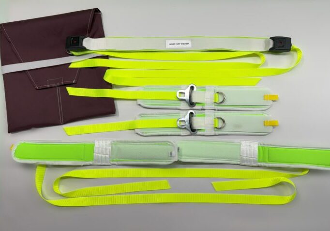 A flurescent lime green and white restraint set on a hospital bed next to a burgundy storage bag.